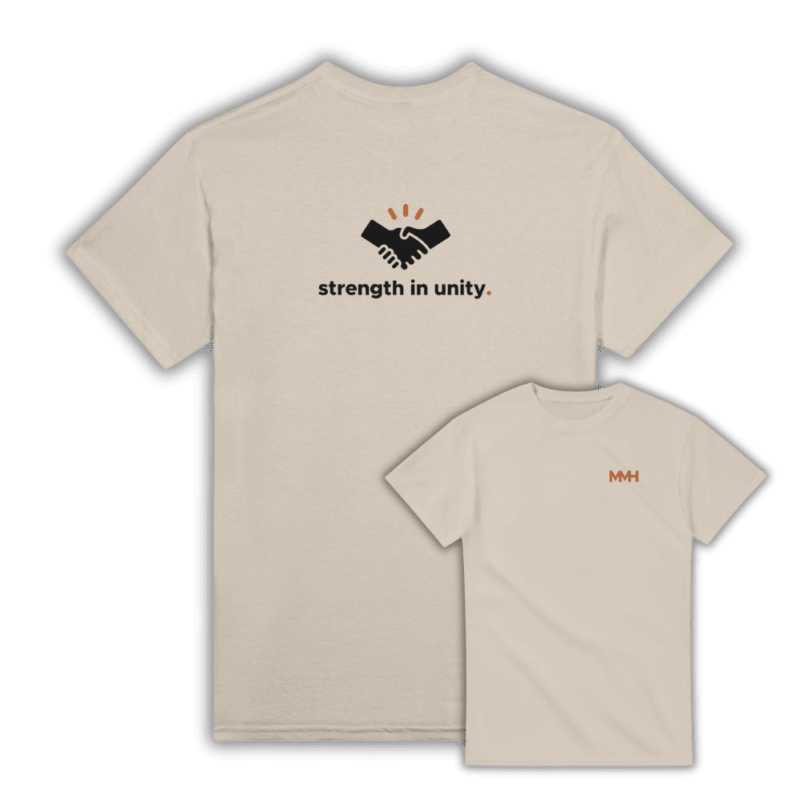 Sand-coloured t-shirt with a back design of a handshake icon and the phrase “strength in unity.” Front features MMH logo in brown to match the design.